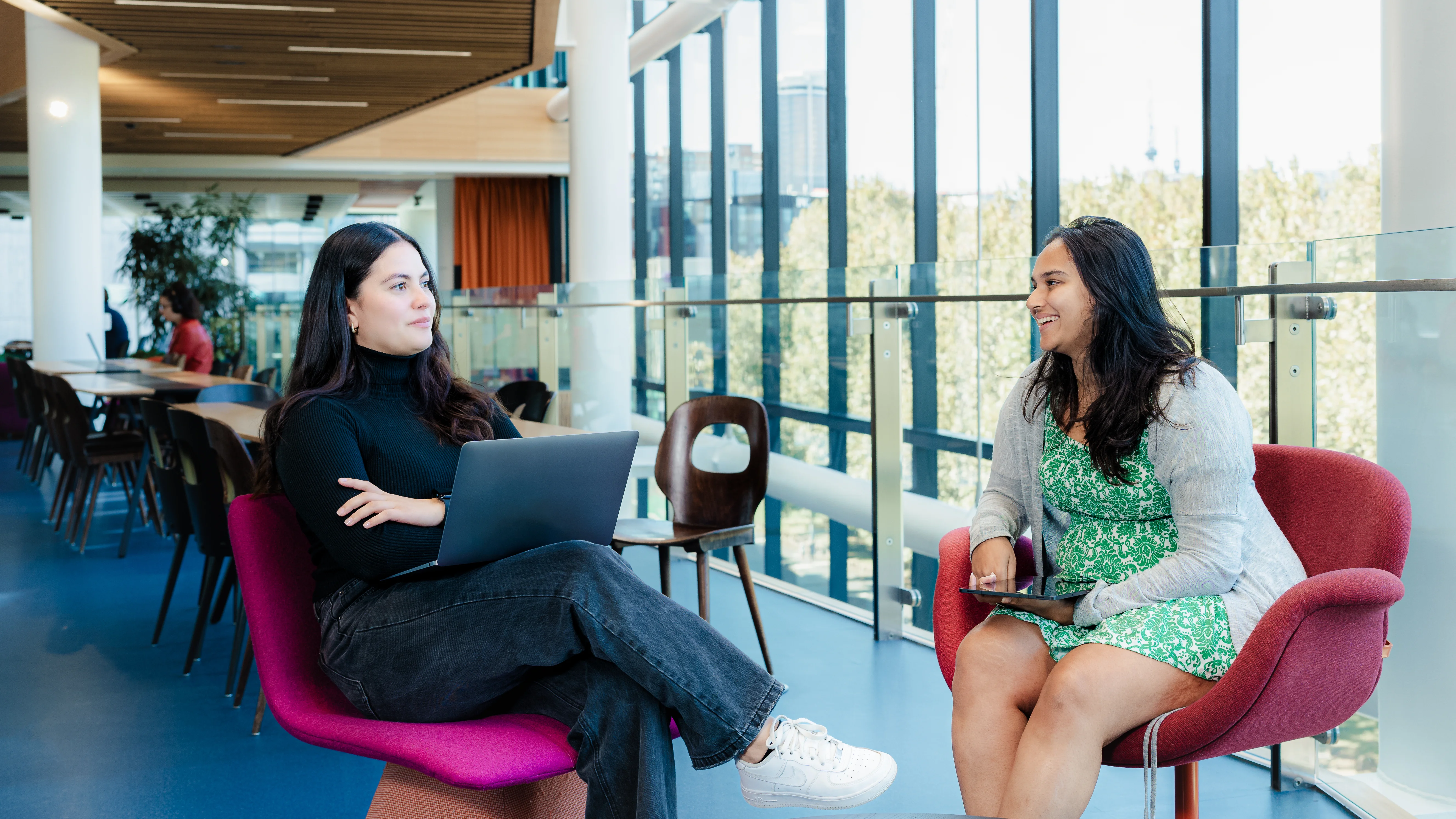 Two woman in an office sitting on chairs talking
