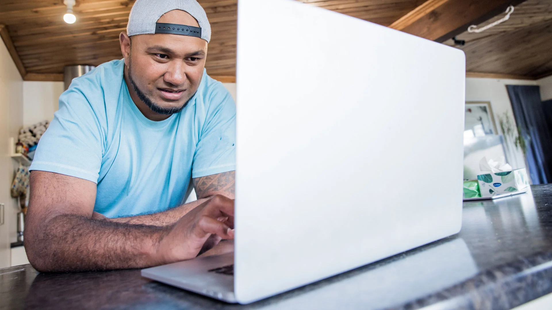 Man writing a CV on his laptop at home.