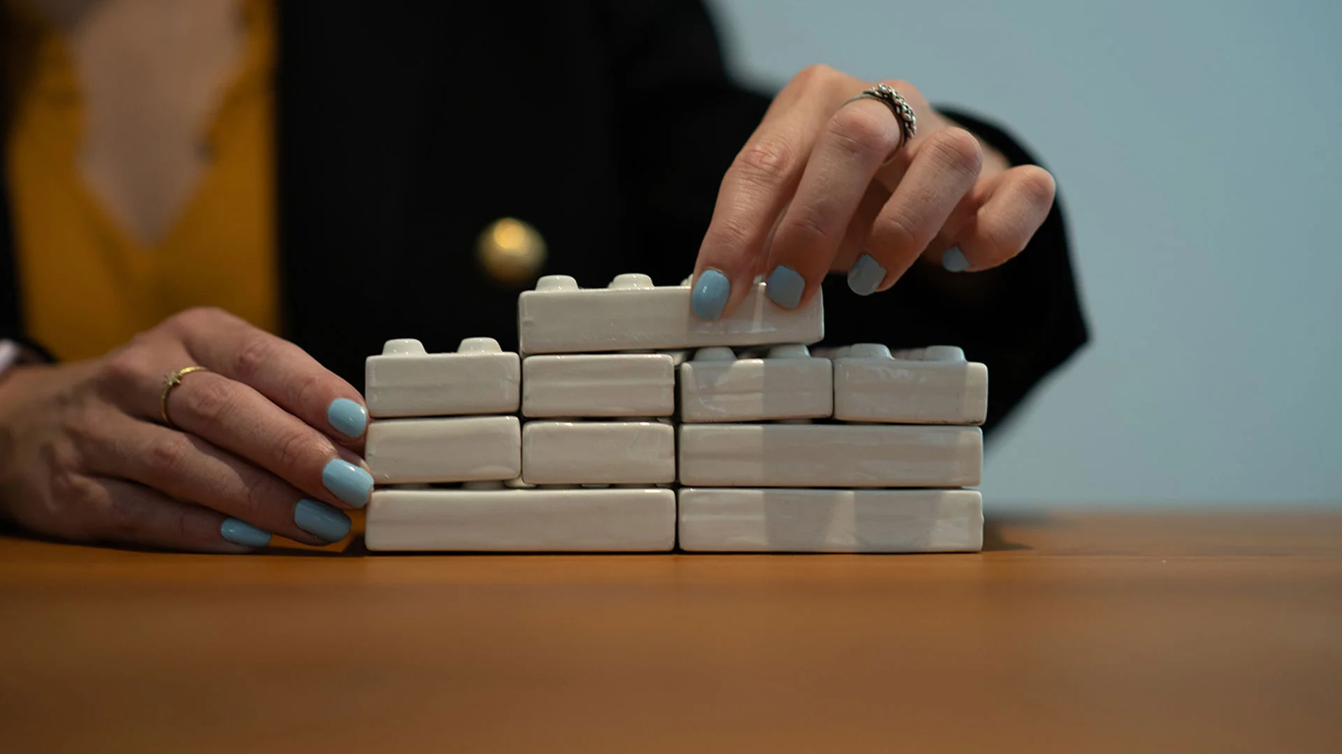 Person stacking up toy blocks in the shape of a house.