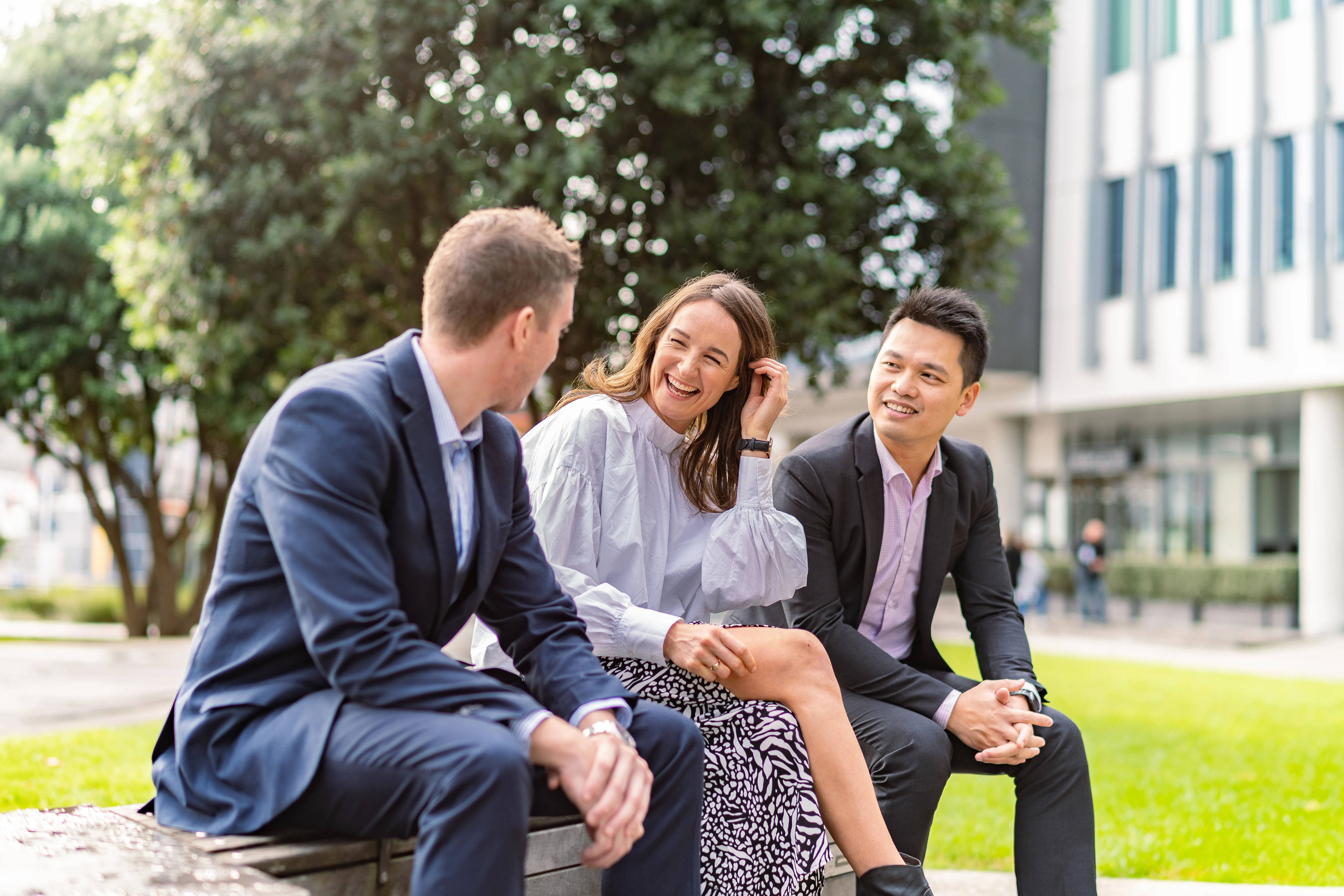 Three people talking outside on a bench